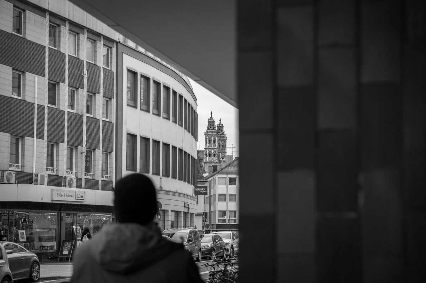 Mainzer Dom, Galeria Kaufhof Person steht in der Stadt, Blick auf Gebäude und Turm im Hintergrund. Schwarz-Weiß-Fotografie.