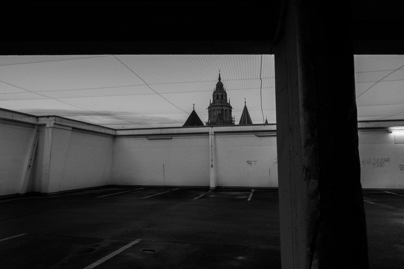 Mainzer Dom St. Martin, Parkhaus Dunkler Parkplatz mit Blick auf eine silhouettierte Stadtansicht im Hintergrund.