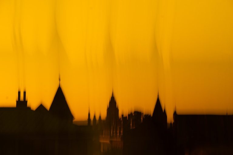 Mainzer Dom St. Martin, Kinoparkhaus Silhouette vom Dom und Gebäuden der Mainzer Altstadt vor einem goldenen, verschwommenen Hintergrund.